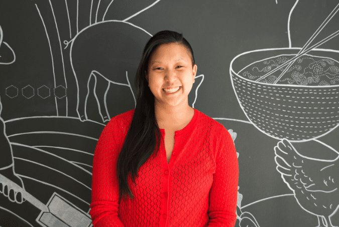 Headshot of a woman smiling to camera, wearing a red cardigan