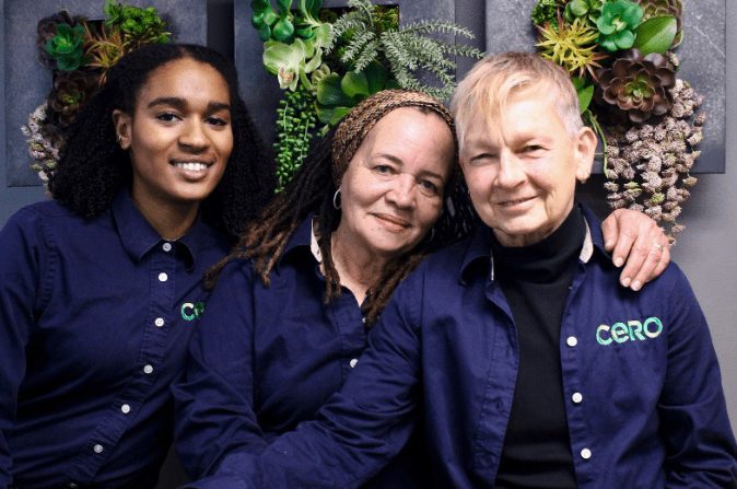 Portrait of three people wearing blue shirts with a logo that reads CERO, looking and smiling at camera