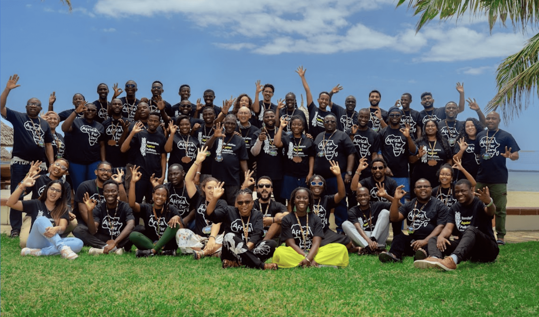 Large group of people posing for a photo. Green grass, blue sky on the background