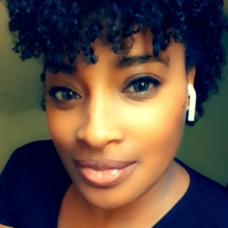 Portrait of black woman looking at camera. Close shot, she's wearing a dark shirt.