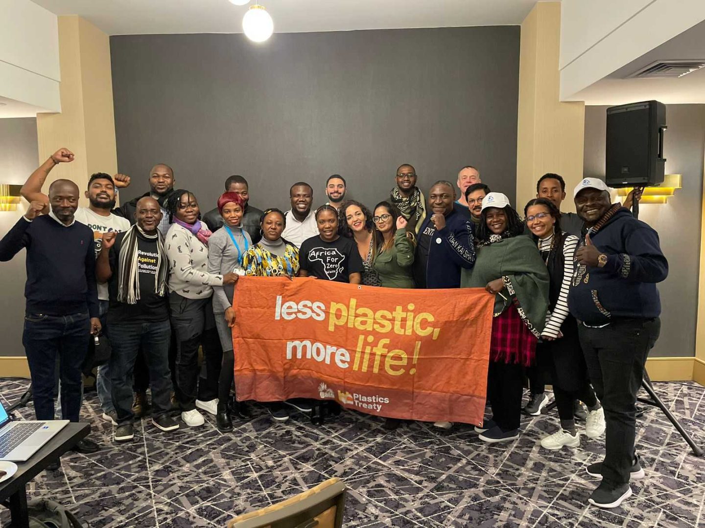 GAIA members from Africa stand in the middle of a room with a streamer that reads: Less Plastic, More Life