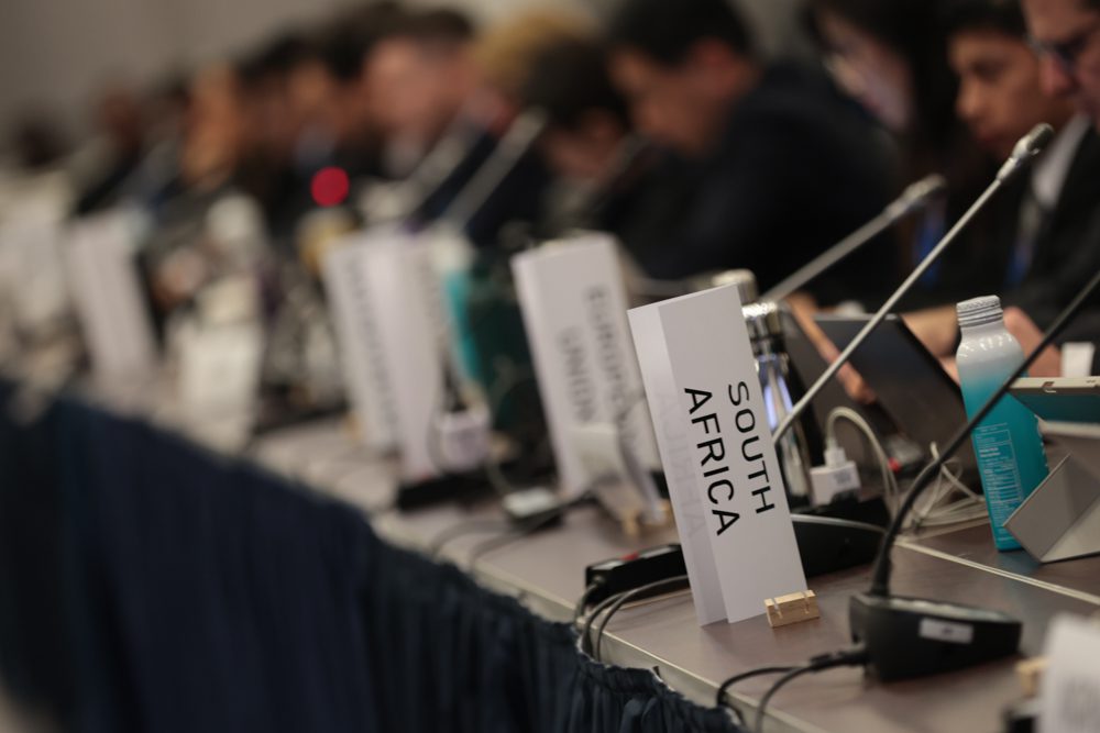 raised cards with names of countries lined up at INC-4 plastics treaty negotiations