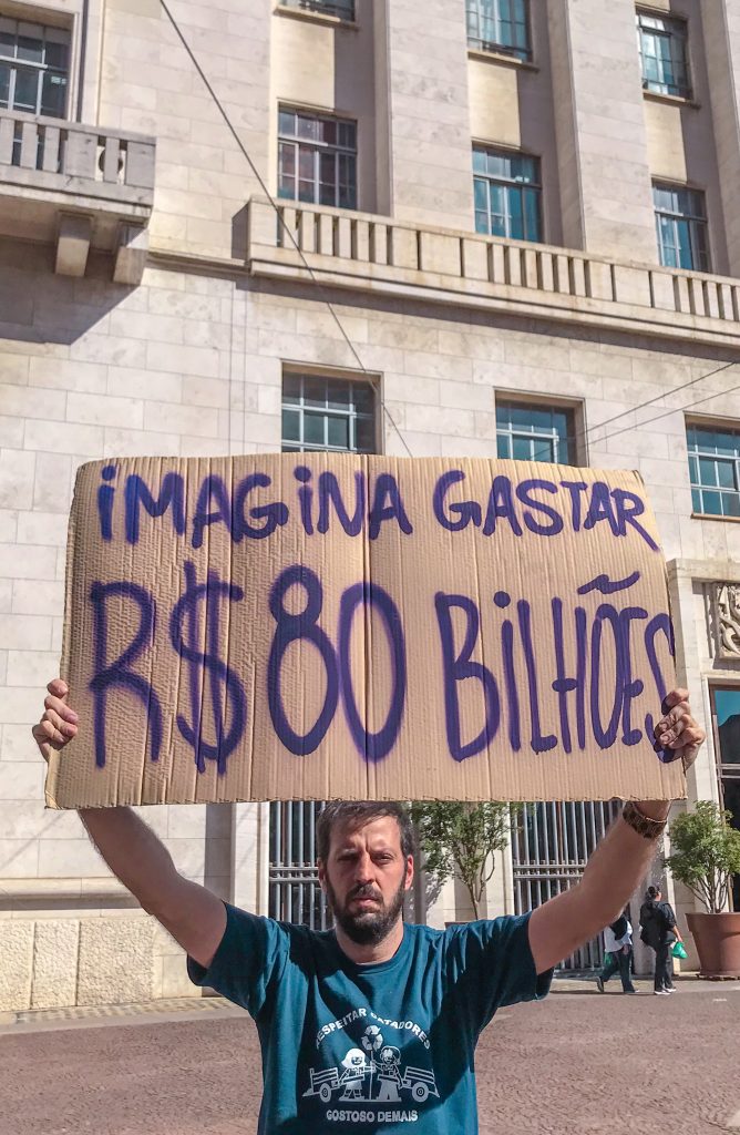 hombre sosteniendo un cartel sobre su cabeza. Al fondo hay un edificio. 