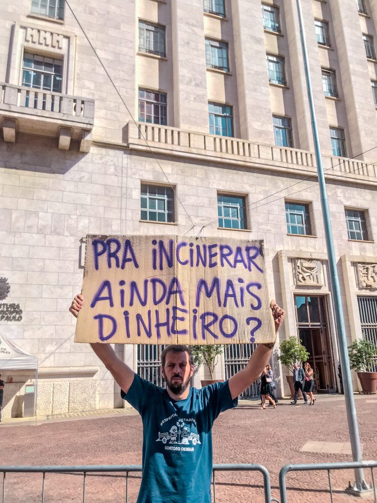 hombre sosteniendo un cartel sobre su cabeza. Al fondo hay un edificio. 