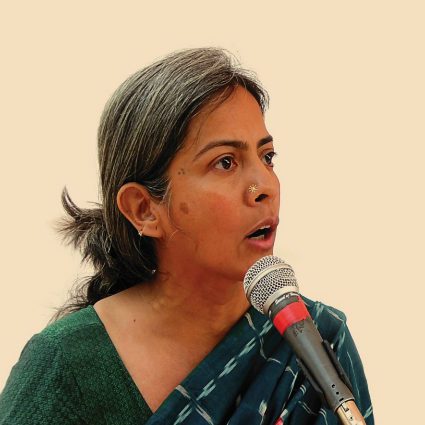 woman wearing a green sari speaking into a microphone