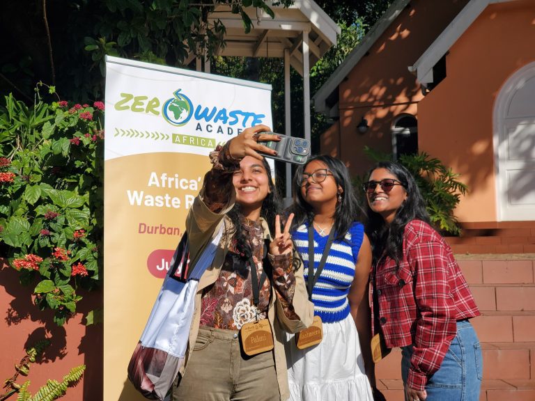 Participants take a selfi in front of Zero Waste Academy Poster